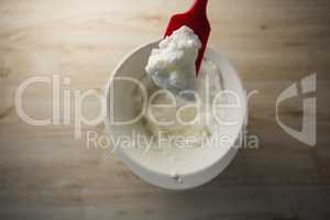 Directly abvoe shot of red spatula with whipped cream