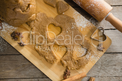 Pastry dough and pastry cutter on cutting board by rolling pin