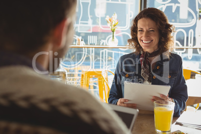 Woman with document looking at man in cafe