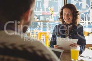 Woman with document looking at man in cafe