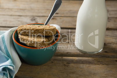 Granola bar and milk with napkin on wooden table
