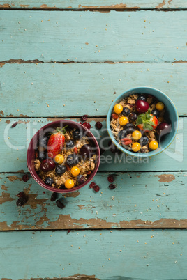 Bowls of breakfast cereals with fruits on wooden table