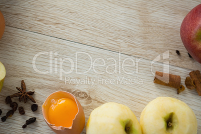Overhead view of apples and spices with broken egg