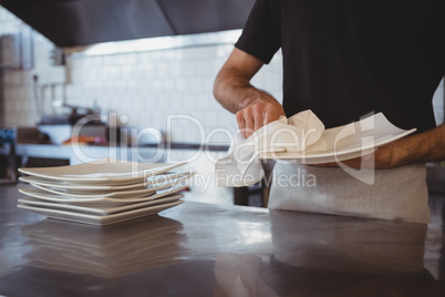 Mid section of waiter cleaning plate in cafe