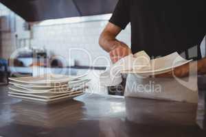 Mid section of waiter cleaning plate in cafe