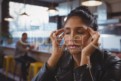 Woman suffering from headache with friend in background