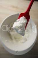 Overhead view of red spatula with whipped cream