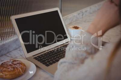 Cropped image of woman with laptop at cafe