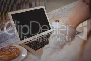 Cropped image of woman with laptop at cafe