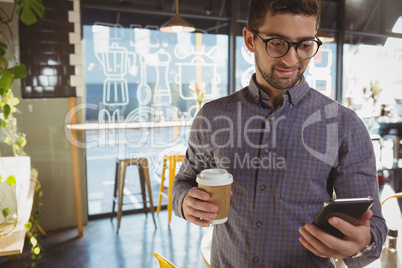 Man using phone while having coffee in cafe