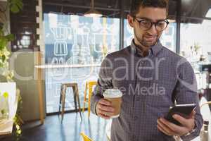 Man using phone while having coffee in cafe