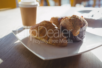Croissants and muffin in plate on table