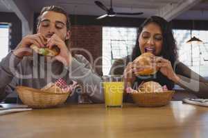 Young friends eating burgers in cafe
