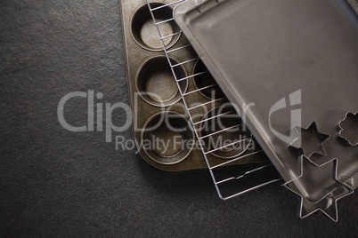 Overhead view of various pastry cutter and baking sheet with cooling rack on muffin tin