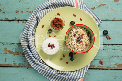 Plate of breakfast cereal with fruits and yoghurt on wooden table