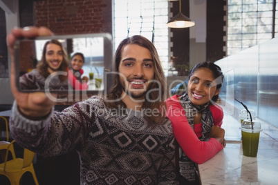 Man with female friend taking selfie in cafe