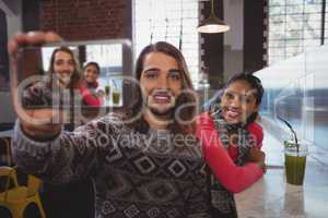 Man with female friend taking selfie in cafe