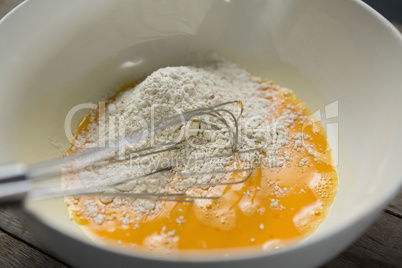 High angle view of flour on egg yolk in container