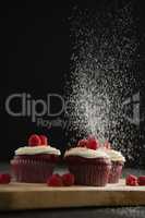 Powdered sugar falling over cupcakes on cutting board