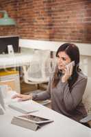 Female executive talking on mobile phone at desk