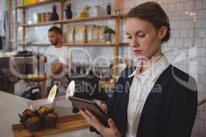 Owner using tablet with waiter working in cafe