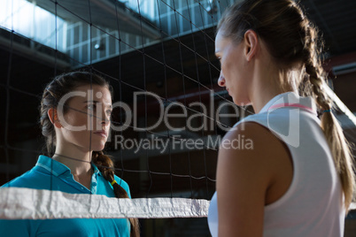 Aggressive female volleyball players looking through net