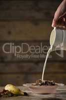 Hand pouring milk on wheat flakes