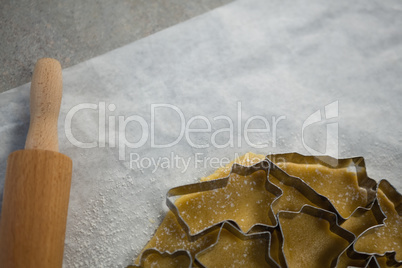 Cropped image of various pastry cutters over dough on wax paper