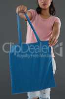 Mid section of young woman holding blue shopping bag