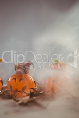 Jack o lantern containers over smoke on table during Halloween