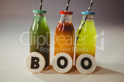 Boo text on cookies by colorful drinks in bottles