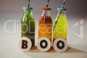 Boo text on cookies by colorful drinks in bottles