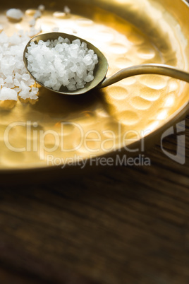 Salt in spoon and plate on wooden table