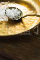 Salt in spoon and plate on wooden table