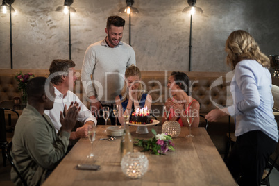 Woman receiving surprise birthday cake from her friends