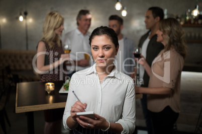 Beautiful waitress writing order in notepad