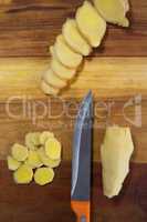 Directly above view of chopped gingers with knife on cutting board