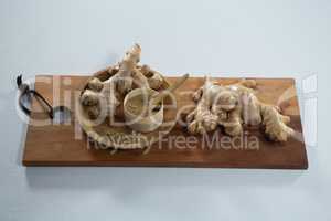 High angle view of ginger and powder in wooden plate on serving board