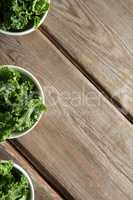 Overhead view of kale in bowls on brown table