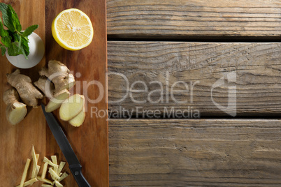 Overhead view of lemon and ginger on cutting board over table