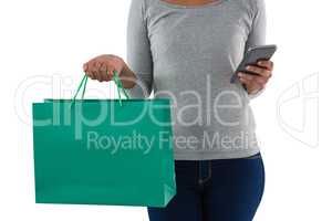 Woman holding shopping bag using mobile phone