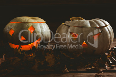 Close up of illuminated kack o lanterns with autumn leaves