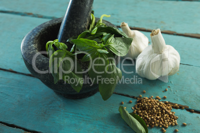 Mortar and pestle with herbs and spices on wooden table