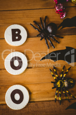 Cookies with boo text by decorations on wooden table