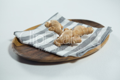 High angle view of fresh ginger on striped napkin in wooden plate
