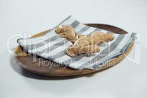 High angle view of fresh ginger on striped napkin in wooden plate