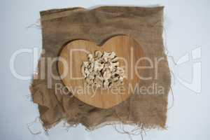 Overhead view of dried gingers on heart shape wooden serving board over burlap