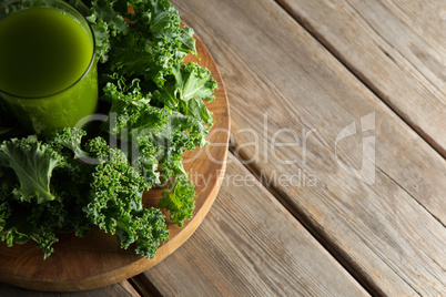 Kale juice in glass with leaves on cutting board