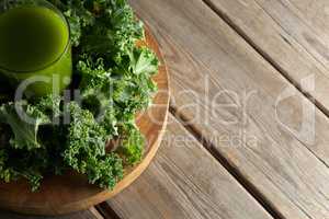 Kale juice in glass with leaves on cutting board