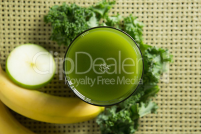 Fresh kale juice in glass with fruits on place mat